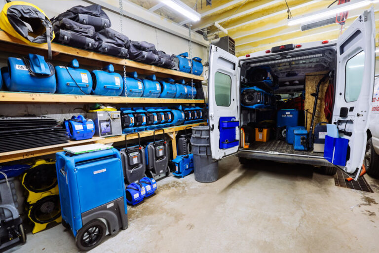 Restoration equipment, including dehumidifiers and air movers, stored in a professional service van.